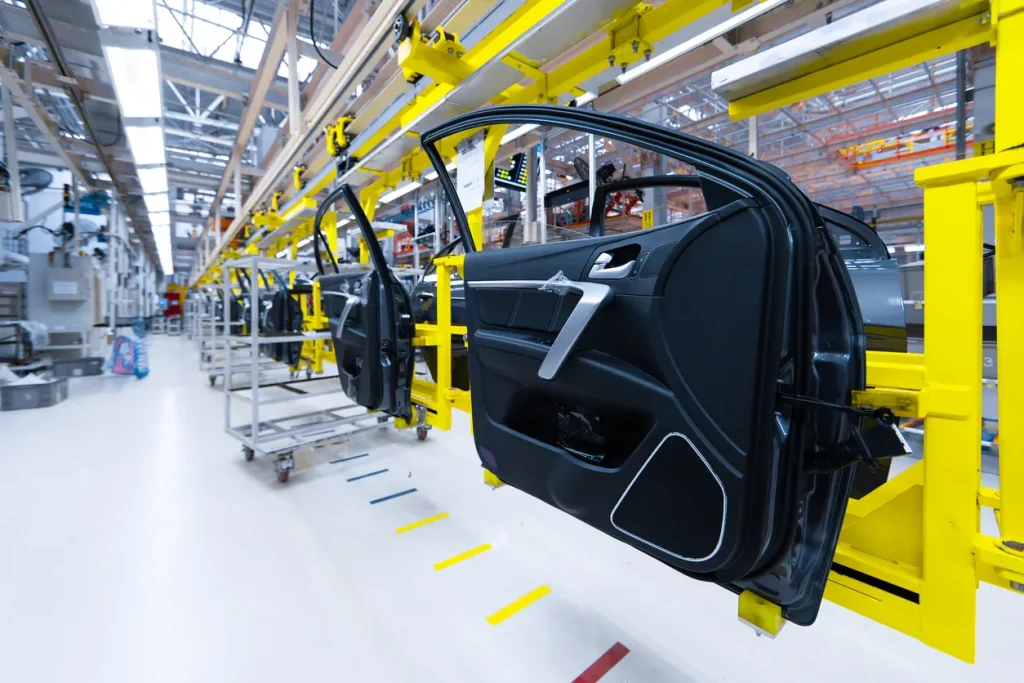 Molded car door panels on an overhead conveyor, the curved grained parts the best industrial sensors for the automotive industry must read.