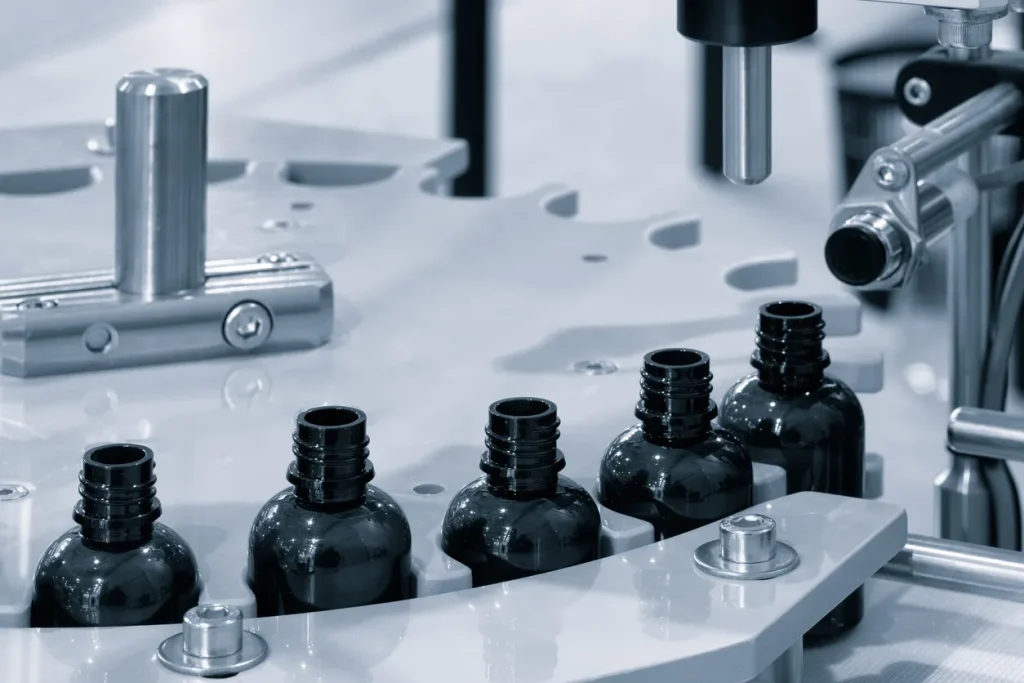 Dark bottles moving through an automated pharmaceutical filling line, the light-blocking packaging behind measuring opacity in plastic containers.