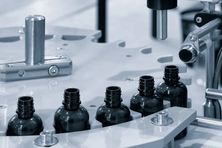 Dark bottles moving through an automated pharmaceutical filling line, the light-blocking packaging behind measuring opacity in plastic containers.